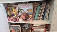 Shelf section with Tea Party, Taste of Home Holiday & Celebrations and stack of other cookbooks
