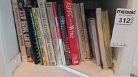 Shelf containing assorted cookbooks and beverage books