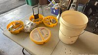 Overview of four yellow organizers filled with hardware and white 5-gallon bucket