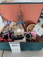 Overall view of box containing tabletop clock and assorted jewelry pieces