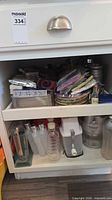 Cabinet view showing paper plates, metal bowls, aluminum trays, disposable supplies