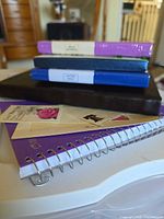 Stack of sealed hardcover notebooks, black journal, stamp sheets and spiral notebook