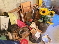 Assorted items piled together showing milk can with sunflowers, wicker basket, waste bin and hardware