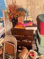 Overall lot showing totes, chest of drawers, folding chairs, floral arrangement