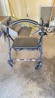 Full view of blue rollator showing seat, backrest, wheels, and brakes
