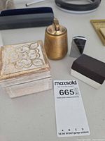 Group shot of brass table lighter, chrome Zippo lighter, wooden box