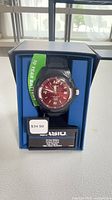 Watch in open retail box showing dial, band, tags and 10-year battery label