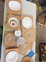 Overhead view of entire eight-piece CorningWare set on cardboard inserts showing unused condition