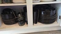 Cabinet view showing stacked plates, bowls, trays, and metal cup racks