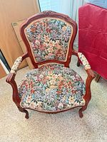 Front view of carved wood armchair showing floral upholstery pattern