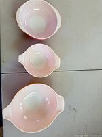 Top-down view of the three nesting glass mixing bowls showing pink interiors and white handles