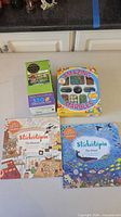 Group shot of puzzle box, marbles box, and two Stickertopia books