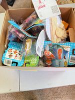 Open box showing numerous sealed Happy Meal toys including bagged Finding Nemo and others, plus wood piece toy on card