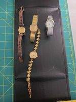 Overview of four wrist watches laid out on mat