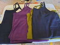 All four folded camisoles showing colors black, purple, olive, navy with straps and tags visible