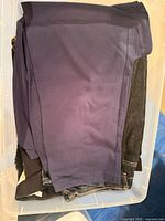 Top view of folded jeans and leggings inside clear plastic bin