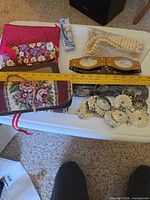 Group view of clutches, belt, pearls, laces, concho clips with measuring tape