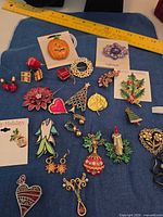 Group shot of all brooches, pins and earrings on blue background