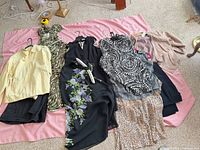 Overview of nine clothing pieces laid out on pink blanket