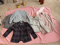 All five women’s tweed/wool jackets laid out on pink fabric
