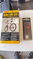 Front of Racor bike lift retail box beside packaged Master cable lock