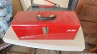 Closed Waterloo red toolbox on table, showing exterior, handle and latch