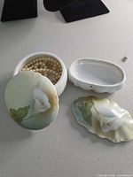 Open round trinket box with necklace inside and oval box parts visible