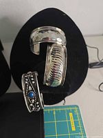Two of the silver-plated cuff bracelets displayed on stand