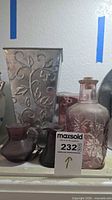 group view showing metal planter, pink glass containers, two purple bud vases, lot tag visible
