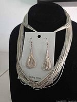 Necklace displayed on black bust with matching earrings on card