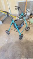 Full view of teal rollator walker showing frame, wheels, seat and pouch