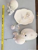 Group shot of six unglazed bisque ceramic items with measuring tape for scale
