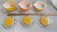 Top view showing three casserole bowls and three sunflower lids with ruler for scale