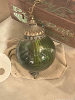 Overall view of green glass globe pendant with chain, canopy and brass-tone fittings