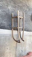 Side profile of wooden runner sled showing curved runners and slatted top