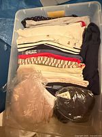 Stack of folded tops in storage bin showing colours and styles