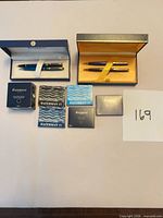 Overview of both pen sets in cases with ink accessories