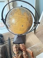 desktop globe with meridian ring and carved figures visible below