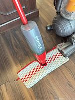 Vileda spray mop head and tank alongside Dyson vacuum base
