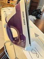 Left side view of the purple and white Black & Decker steam iron showing handle, cord and soleplate