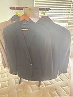 Three black blazers on hangers