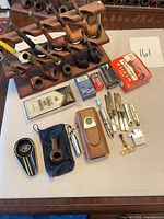 Group shot of all items: 10 pipes in rack, cleaners, filters, lighters, knives, tools, cases