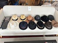 Front view of 12 hats and 2 scarves displayed on sofa