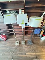 Three floor lamps standing side by side showing overall design, bases, poles, and shades