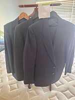 Front view of three suit jackets hanging, showing colors and patterns