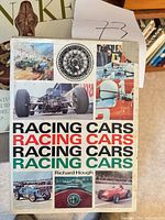 Front cover of Racing Cars by Richard Hough with dust jacket, partial view of snake book behind