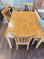 Top view of maple dining table with three chairs visible