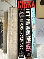 Group of book spines: The Mask of Command, Little Man, Mastering Wine, others