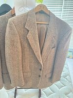 Front view of blazer on hanger showing herringbone pattern and two-button closure