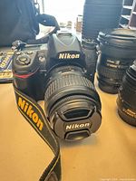 Camera body front with 18-55 mm lens attached; additional lenses visible